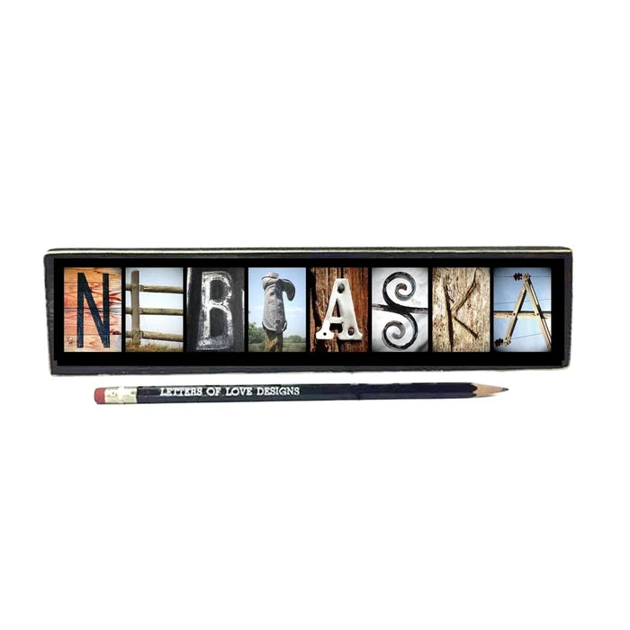 Nebraska-themed decorative sign with wooden letter blocks and a pencil on a white background