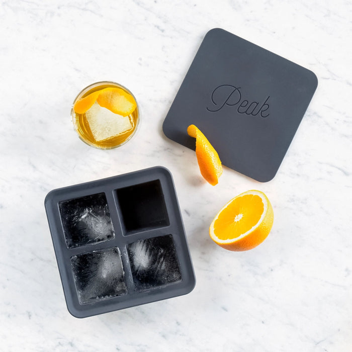 Silicon square ice cube tray by peak on a marble surface with orange and cocktail