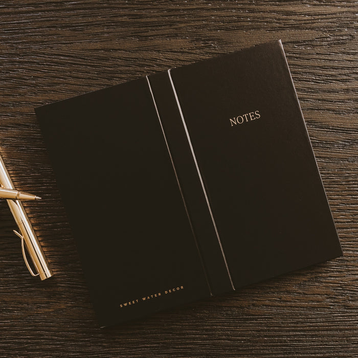Black NOTES sticky notes booklet by Sweet Water Decor displayed with gold pen on wooden desk